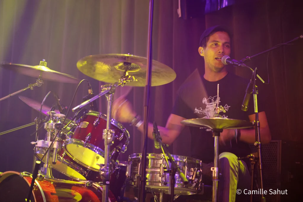 Amine, batteur de Basket Case, jouant de la batterie sur scène pendant un concert.